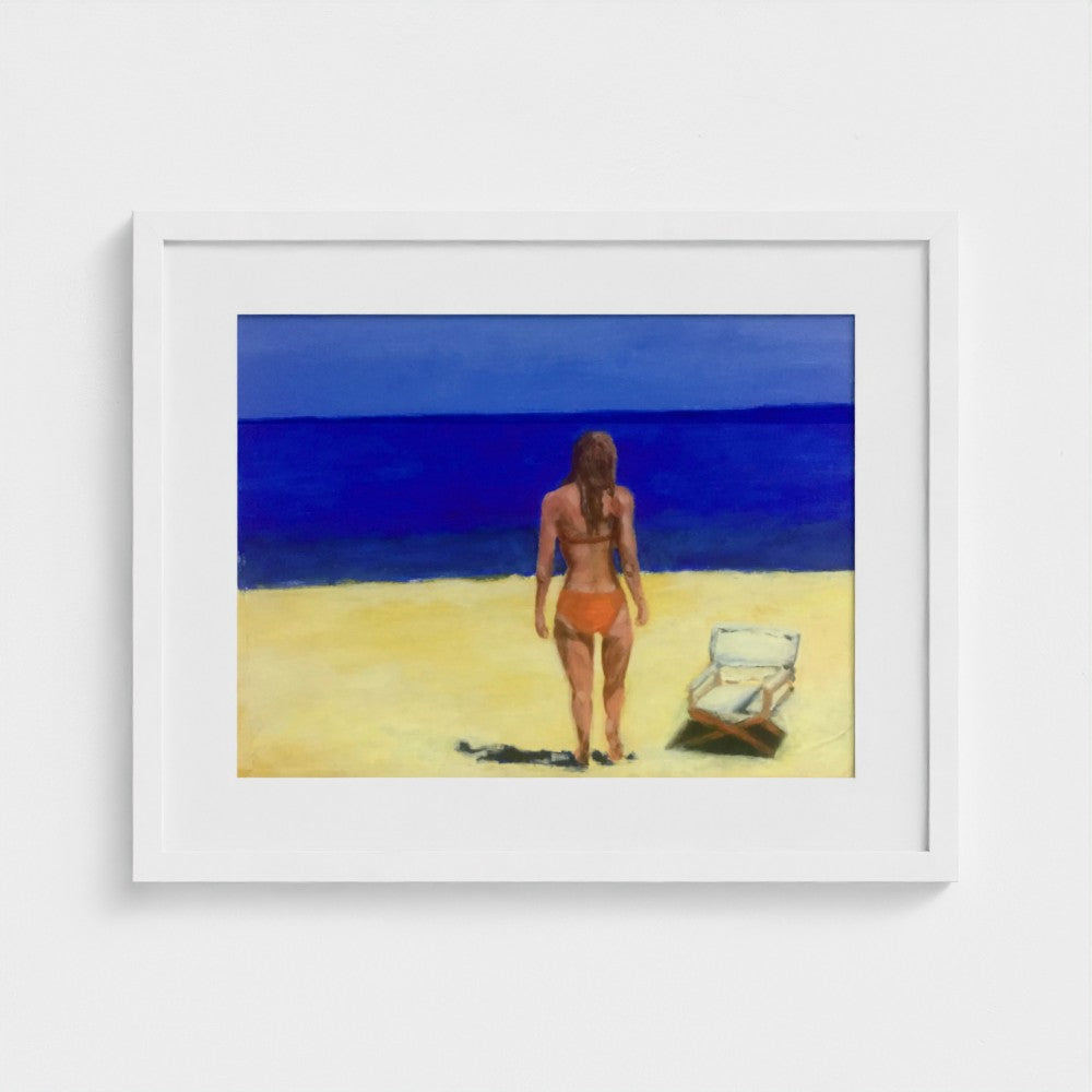 White-framed Formentera beach print by Colin Galloway, with a woman facing blue sea beside a sun lounger.