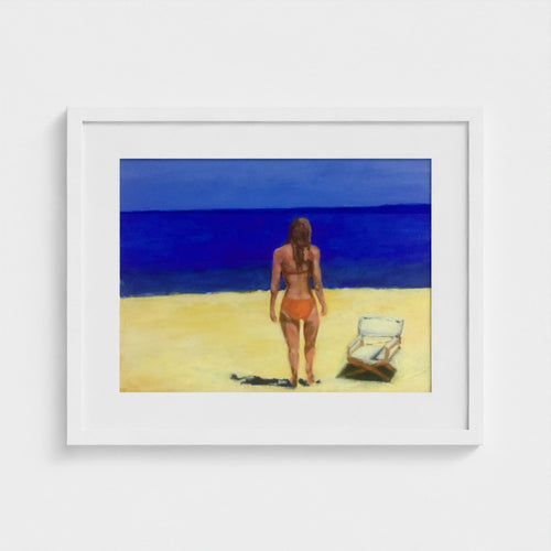 White-framed Formentera beach print by Colin Galloway, with a woman facing blue sea beside a sun lounger.