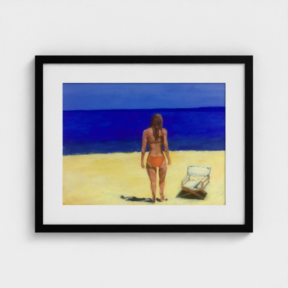 Black-framed Formentera beach print by Colin Galloway, with a woman facing blue sea beside a sun lounger.